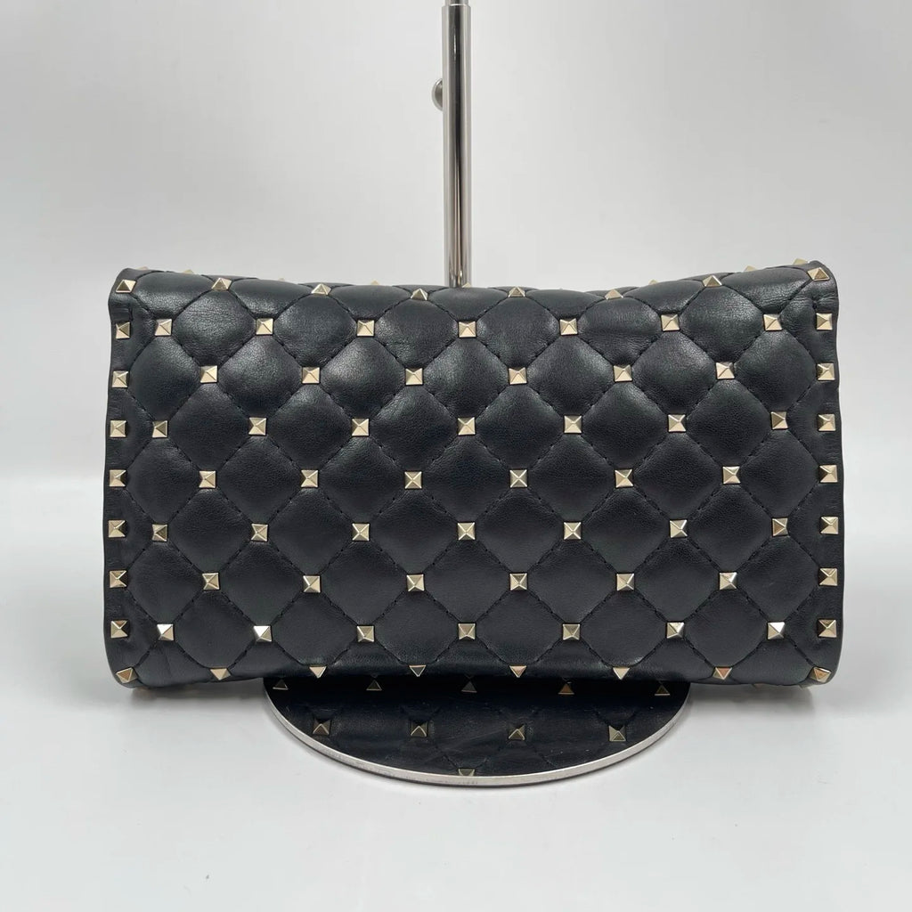 Pre-owned black quilted leather designer handbag with gold pyramid stud rivets, styled as a luxury shoulder bag.