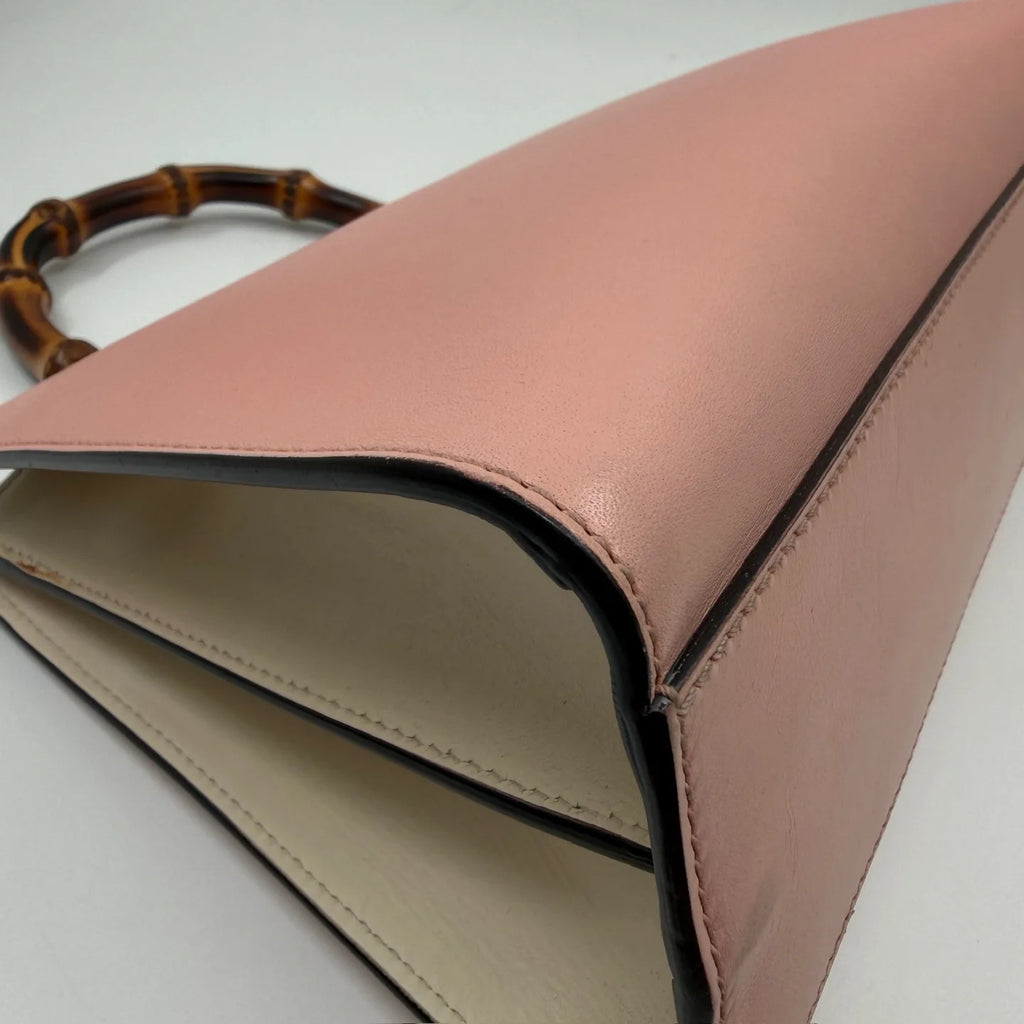 Pre-owned designer handbag in blush pink leather with a cream interior and iconic bamboo top handle.