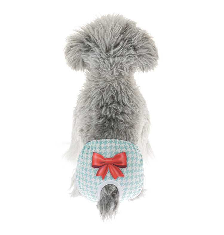 Small dog wearing washable, reusable blue houndstooth sanitary diaper with red bow for female pet hygiene.