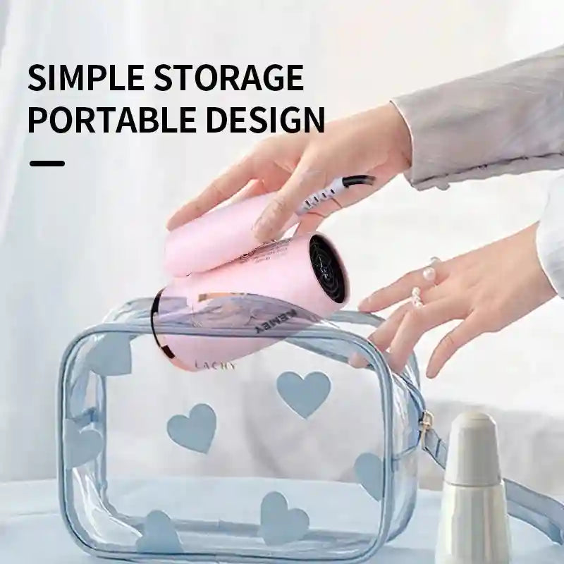 Pink Kemei foldable travel hair dryer being packed into a compact clear heart-pattern bag for easy storage.