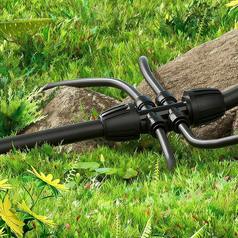 Black dripline tubing with multi-outlet coupler along rocks in a garden bed