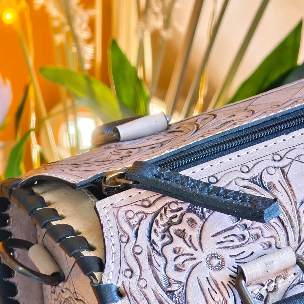 Luxury hand-tooled floral carved leather weekender duffle bag with black stitched trim and brass hardware detail.