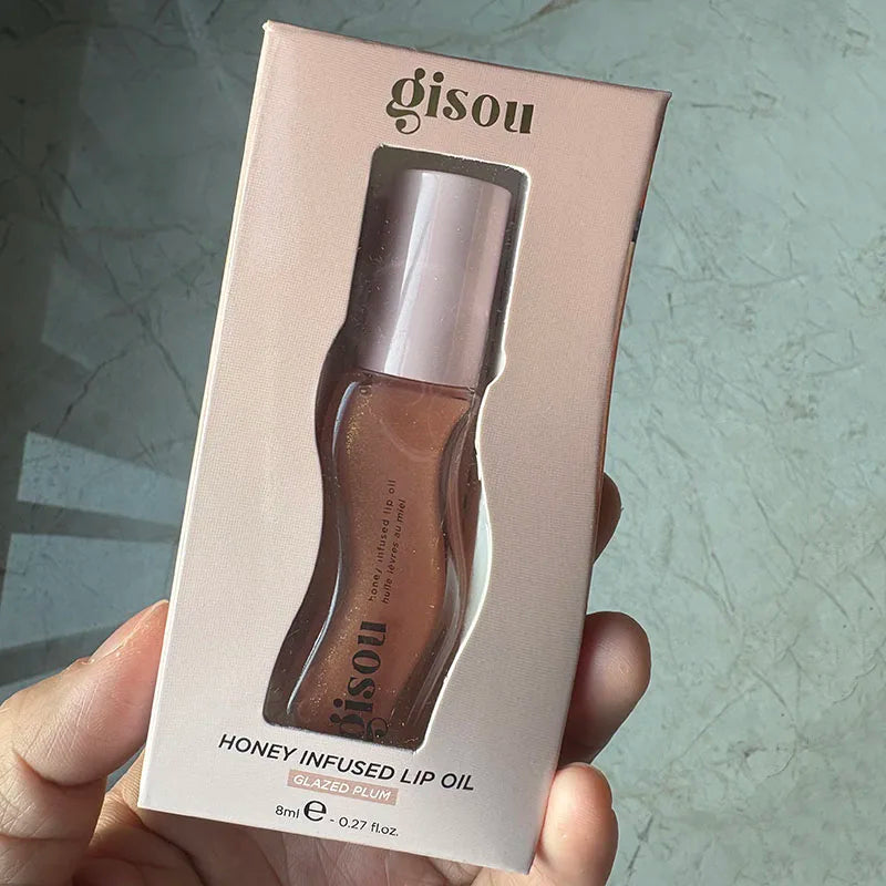 Gisou Honey Infused Lip Oil in Glazed Plum, a hydrating, glossy treatment in a convenient 8ml travel-friendly box.