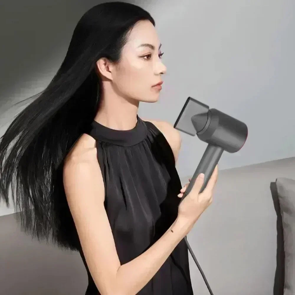 Woman using a grey 5-in-1 ionic hair dryer with styling nozzle for a professional, lightweight blowout.