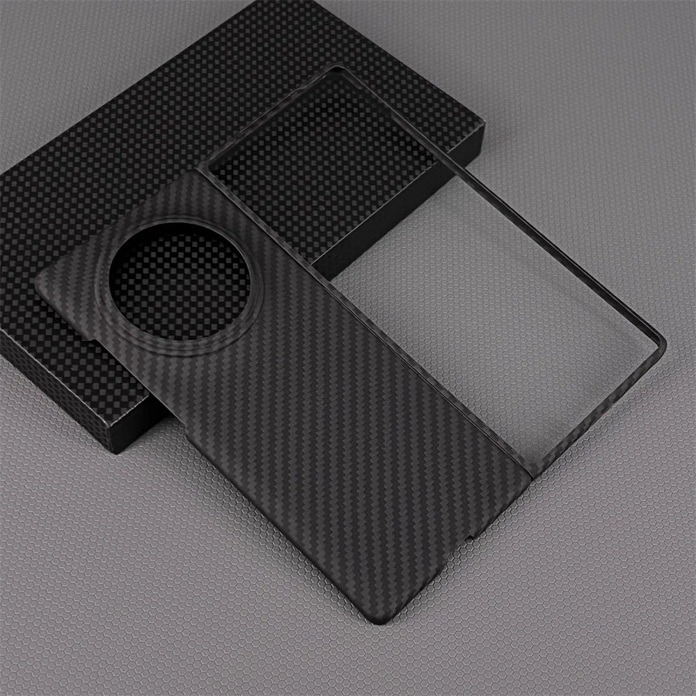 Black carbon fiber phone case with circular camera cutout, resting on its matching box packaging.