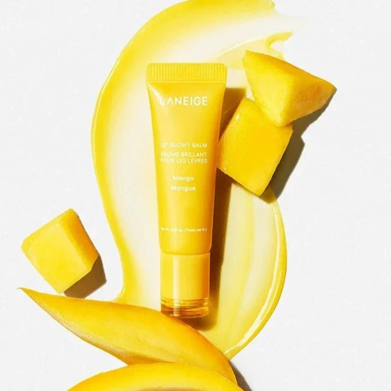 Laneige Lip Glowy Balm in Mango with yellow serum texture and fresh mango fruit slices on a white background.
