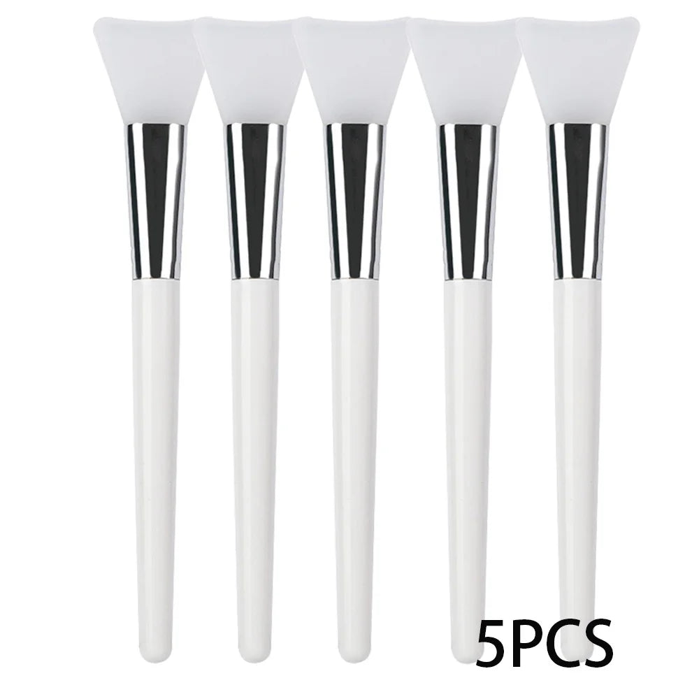 Five silicone face mask applicator brushes with white handles, silver ferrules, and soft, flexible white silicone tips.