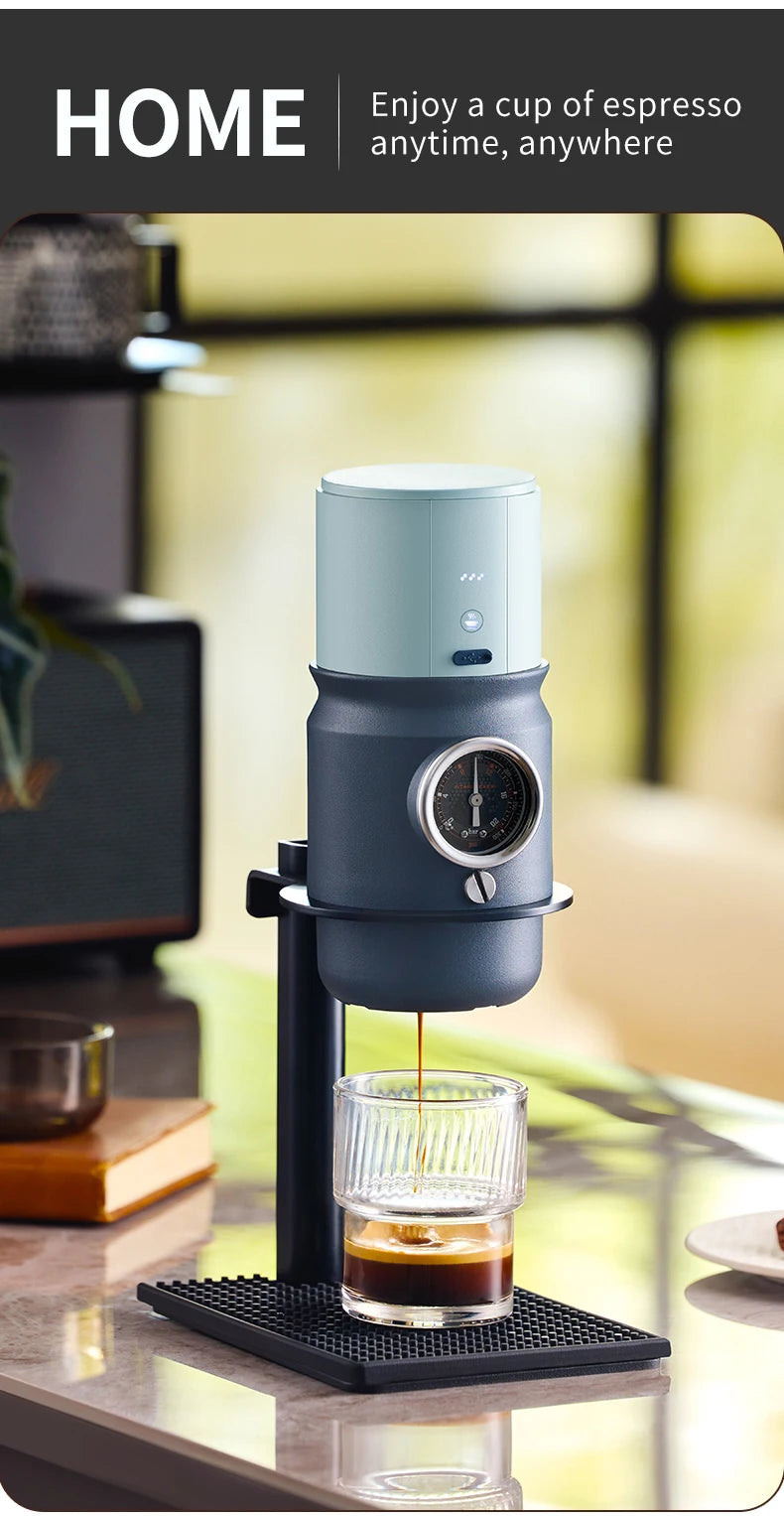 Compact blue and grey manual espresso maker with integrated pressure gauge, brewing coffee into a glass cup.