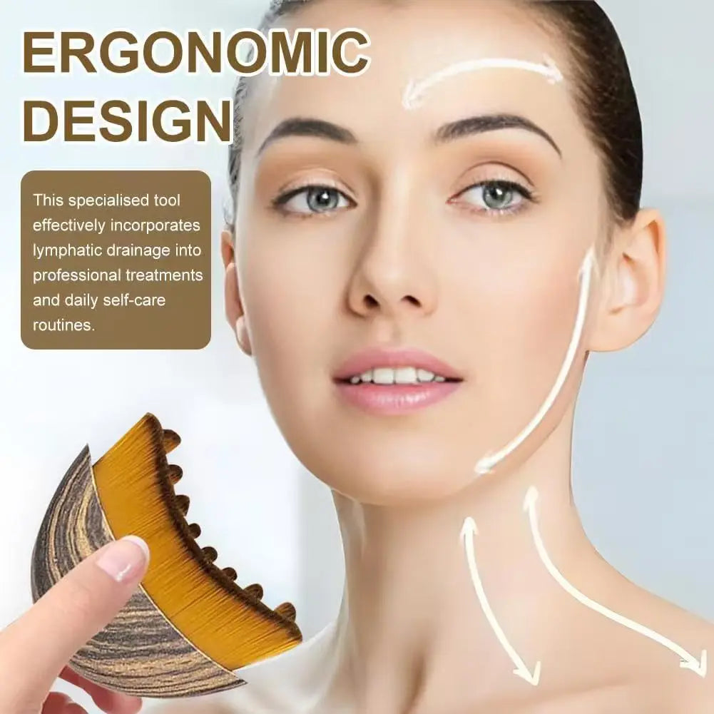 Hand holding a wooden-patterned contour facial brush with golden bristles used for lymphatic drainage massage.