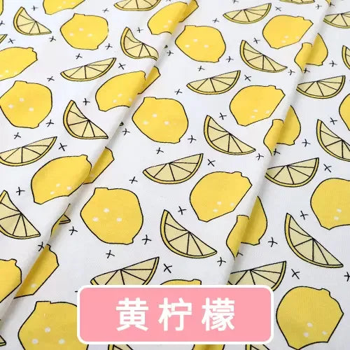 Soft white organic knit jersey fabric featuring a yellow lemon and lemon slice print with small black crosses.