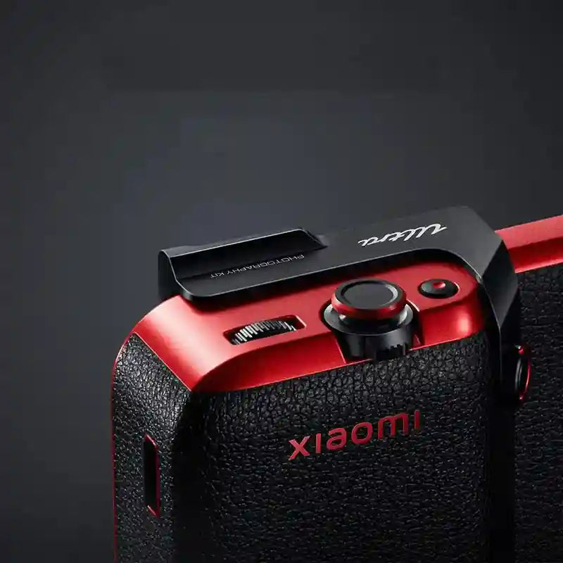 Black and red camera photography kit attachment with a textured grip, shutter button, and dial for smartphone control.