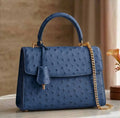 Blue ostrich leather luxury designer handbag with gold chain strap, top handle, and classic vintage aesthetic.