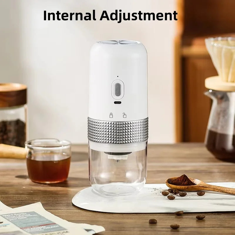 White portable electric coffee grinder with clear bean container, silver texture grip, and internal grind adjustment.