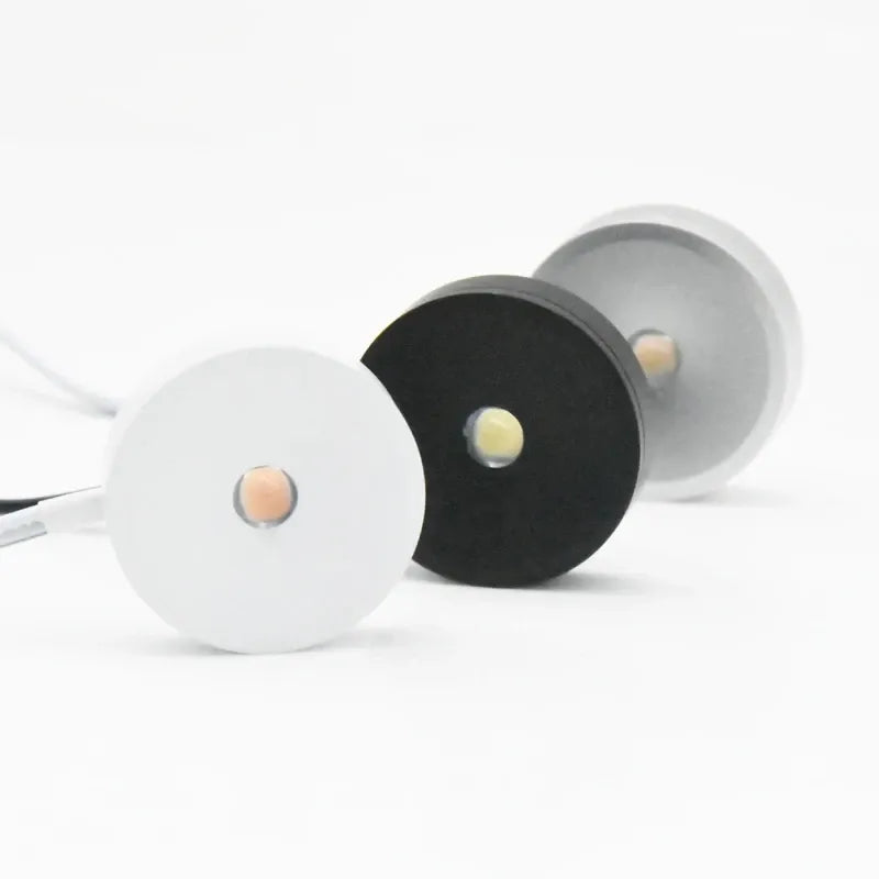 Flat recessed puck lights in white and black with exposed LED lenses