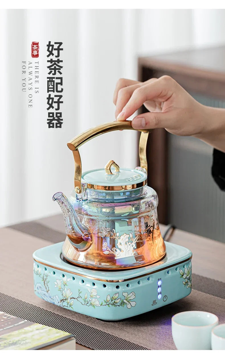 Iridescent glass teapot with gold handle on an electric ceramic floral heating base by There Is Always One For You.