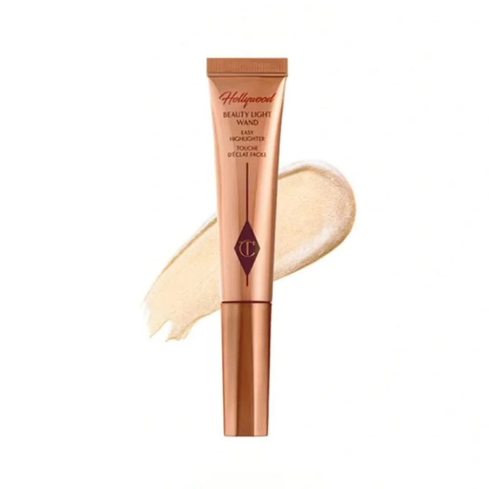 Charlotte Tilbury Hollywood Beauty Light Wand in rose gold tube with shimmering champagne liquid highlighter swatch.