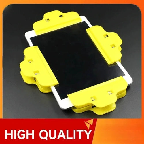 Four yellow Tidesmit plastic spring clamps secured to the edges of a mobile device screen for repair.