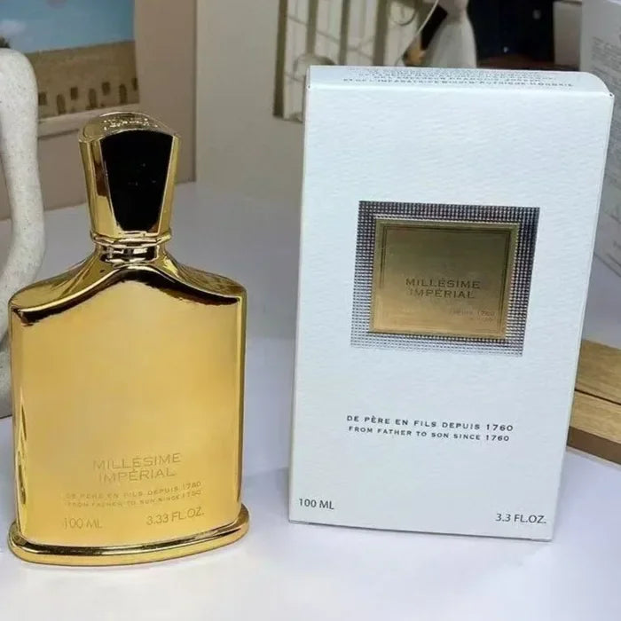 Millesime Imperial 100ml perfume bottle in gold, next to its white rectangular product box.