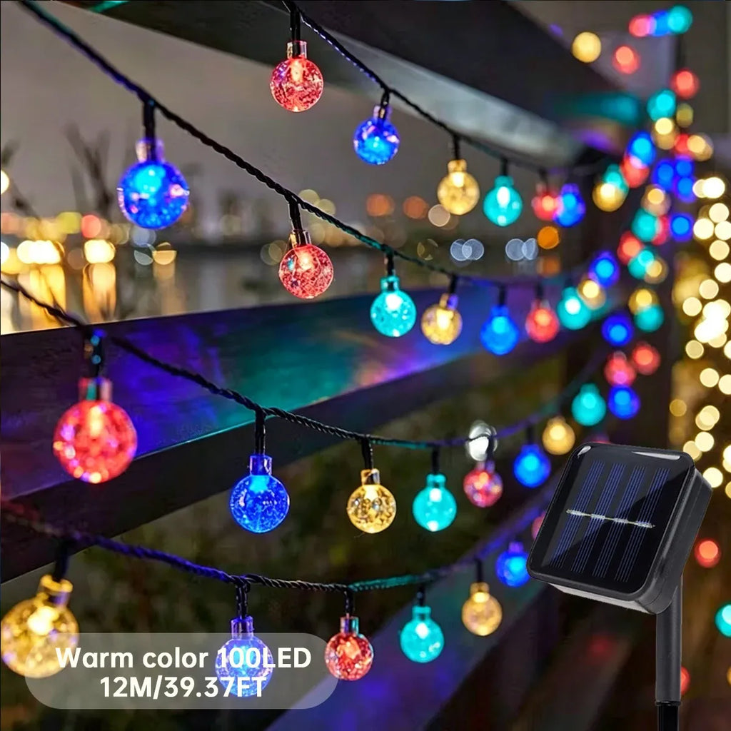 Color-changing LED globe string lights with multicolor bulbs and a solar panel stake outdoors.