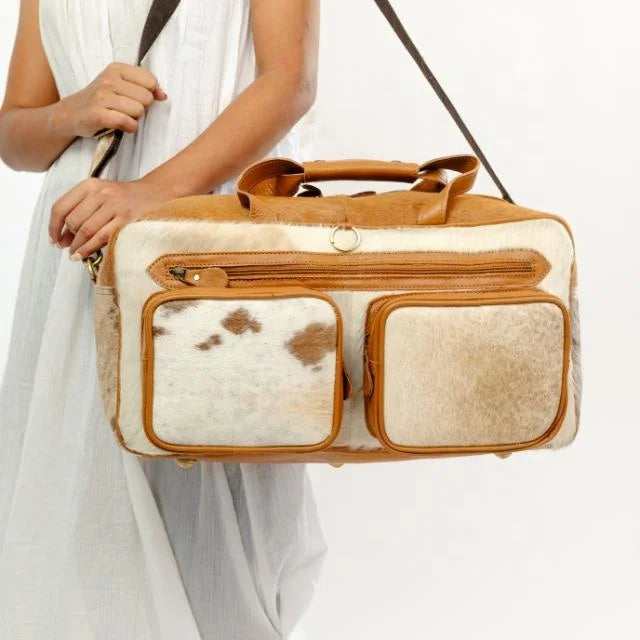 Western-style genuine leather and cowhide duffel bag with front pockets and shoulder strap for travel.
