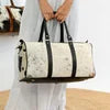 Unisex cow hair-on-hide weekender duffel trunk with black leather trim, carry handles, and natural speckled print.