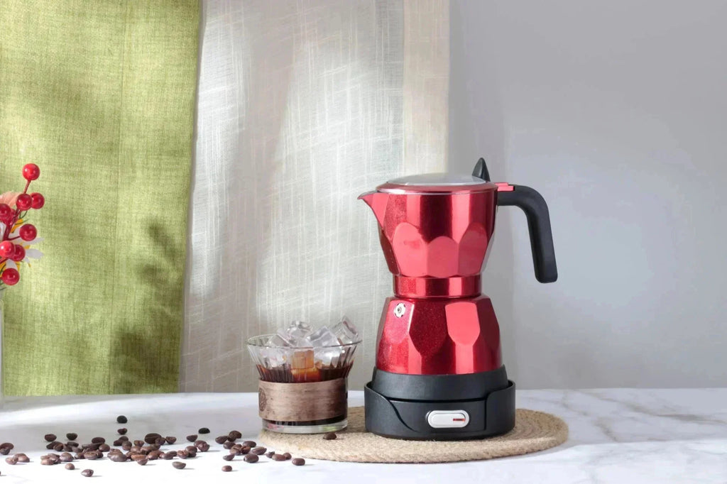 Metallic red electric moka pot coffee maker with black base and handle on a kitchen table with coffee beans.