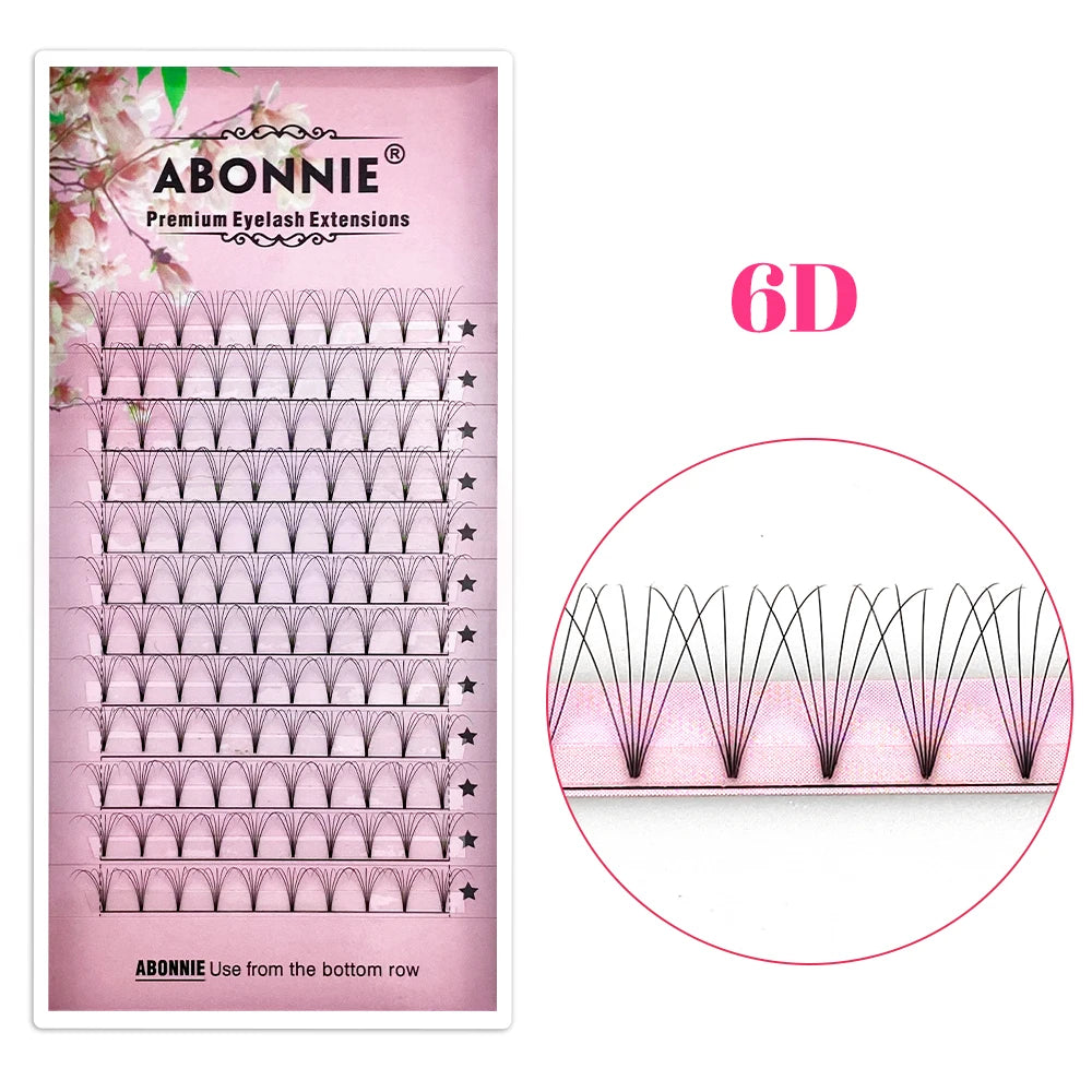 Tray of black ABONNIE 6D premade volume eyelash extension fans with short stems on a pink floral background.