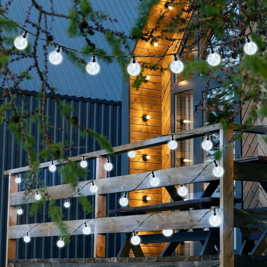 Warm white solar bubble ball string lights draped across an outdoor wooden railing