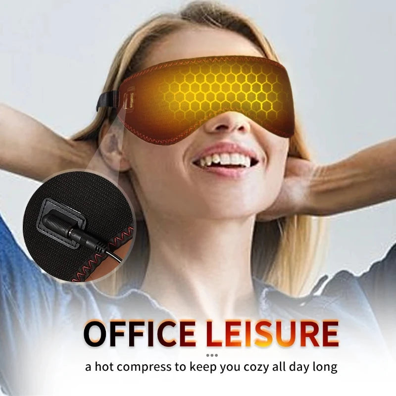 A woman wears a brown heated eye mask with a glowing yellow honeycomb pattern, featuring a plug-in cord detail.