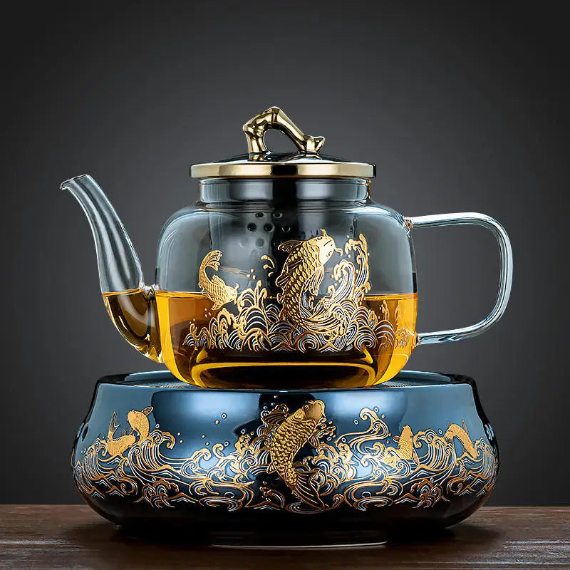 Glass teapot with gold koi fish design on a matching blue decorative warmer base, elegant tea set for loose tea.