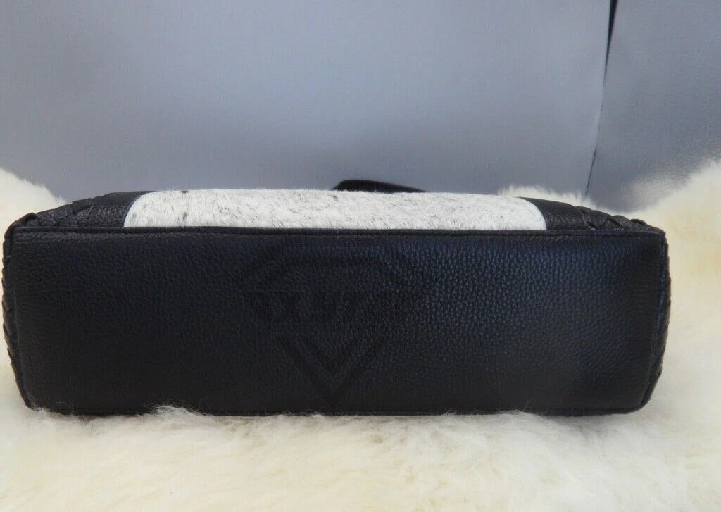 Luxury designer tote: black pebbled leather and white cowhide fur patchwork handbag with woven edge detail.