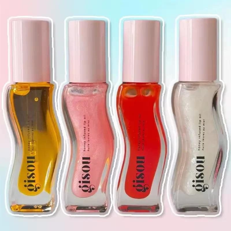 Four Gisou Honey Infused Lip Oil tubes in yellow, pink, red, and clear shades for moisturizing and glossy lip care.