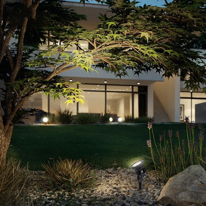 Outdoor LED landscape spike light illuminating garden plants with a black spotlight head