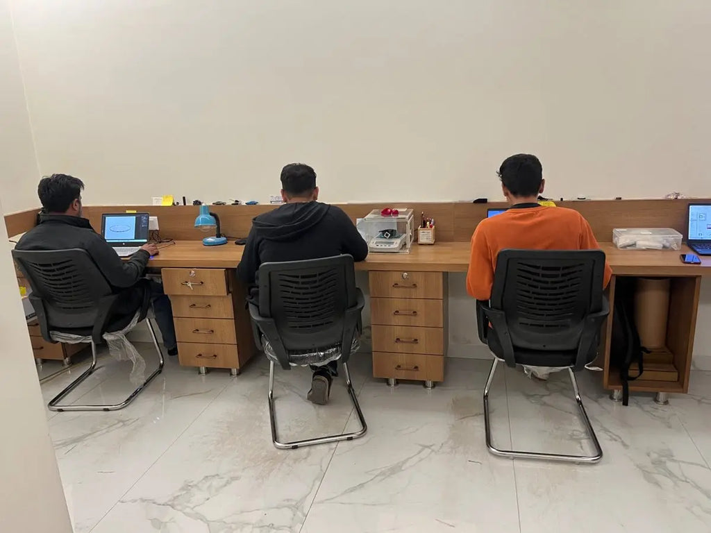 Team working at jewelry benches with tools and supplies in a workshop room
