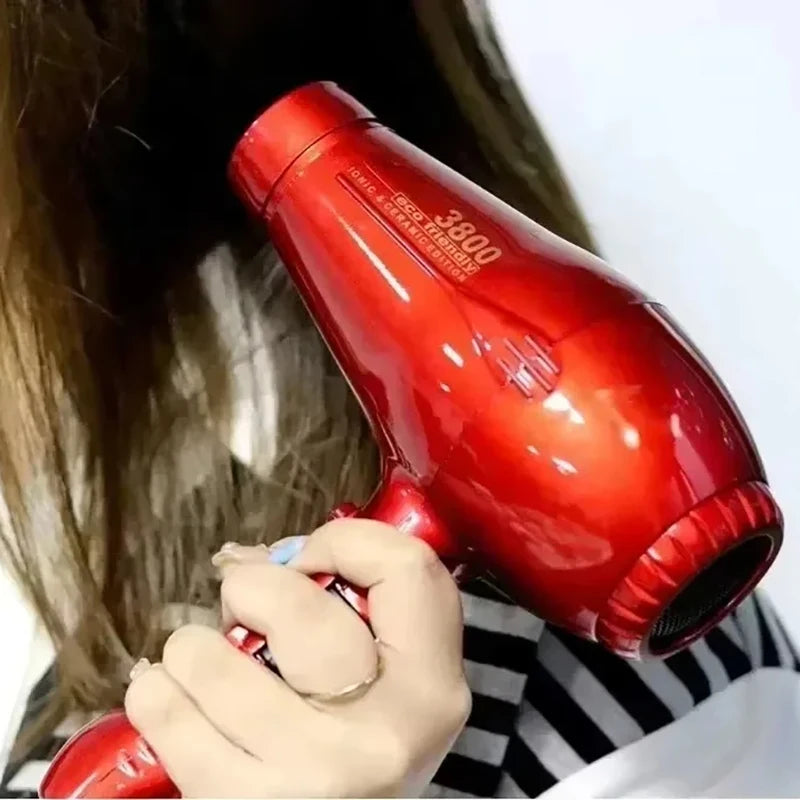 Glossy red 2100W ionic ceramic hair dryer being used to style hair, featuring high-speed drying and professional design.