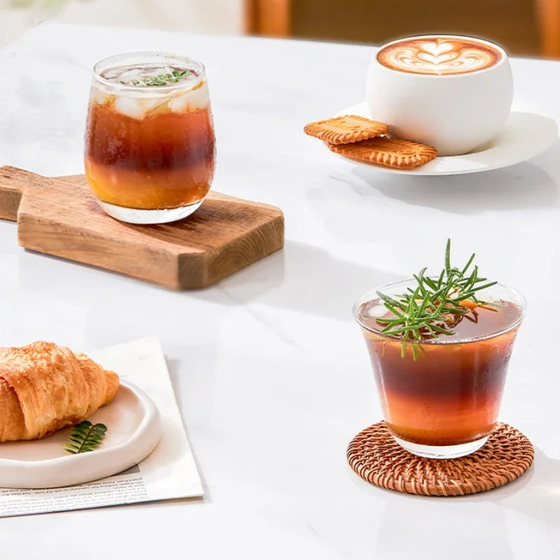 Clear glass coffee cups for iced coffee and lattes on a marble table with pastries and coasters.