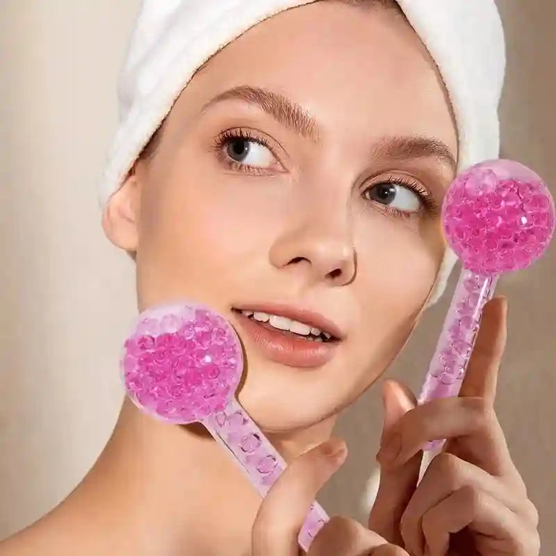 A person with a white headband holds two round, pink, glitter-filled glass facial cooling globes.