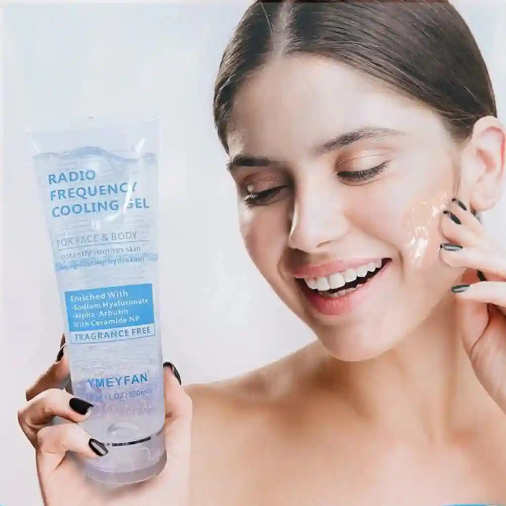 A woman smiling while applying clear YMEYFAN radio frequency cooling gel from a 300ml squeeze tube onto her cheek.