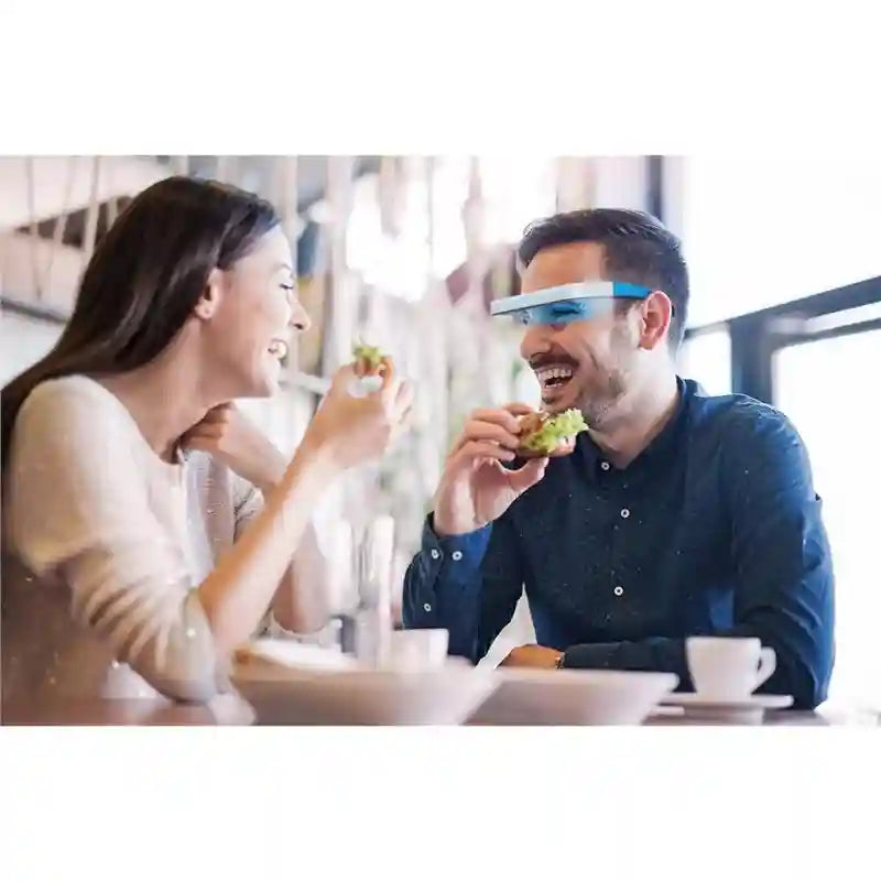 Man wearing blue and white UV-free light therapy glasses for sleep and energy while eating with a friend.