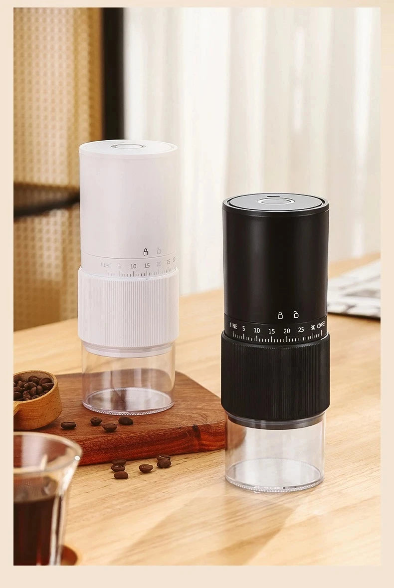 Portable manual coffee bean grinders in black and white with adjustable grind settings and clear containers on wood.