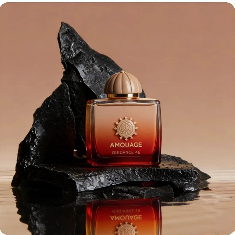 Guidance 46 perfume in a square, orange-to-red ombre glass bottle with a round cap, set on black volcanic rock.