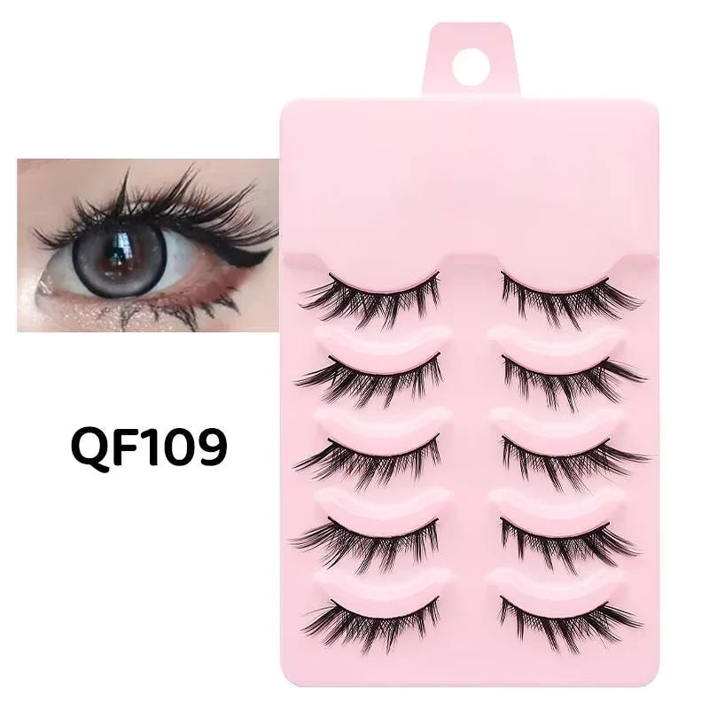 Five pairs of black, wispy manga-style false eyelashes arranged on a pink plastic tray with an eye makeup example.