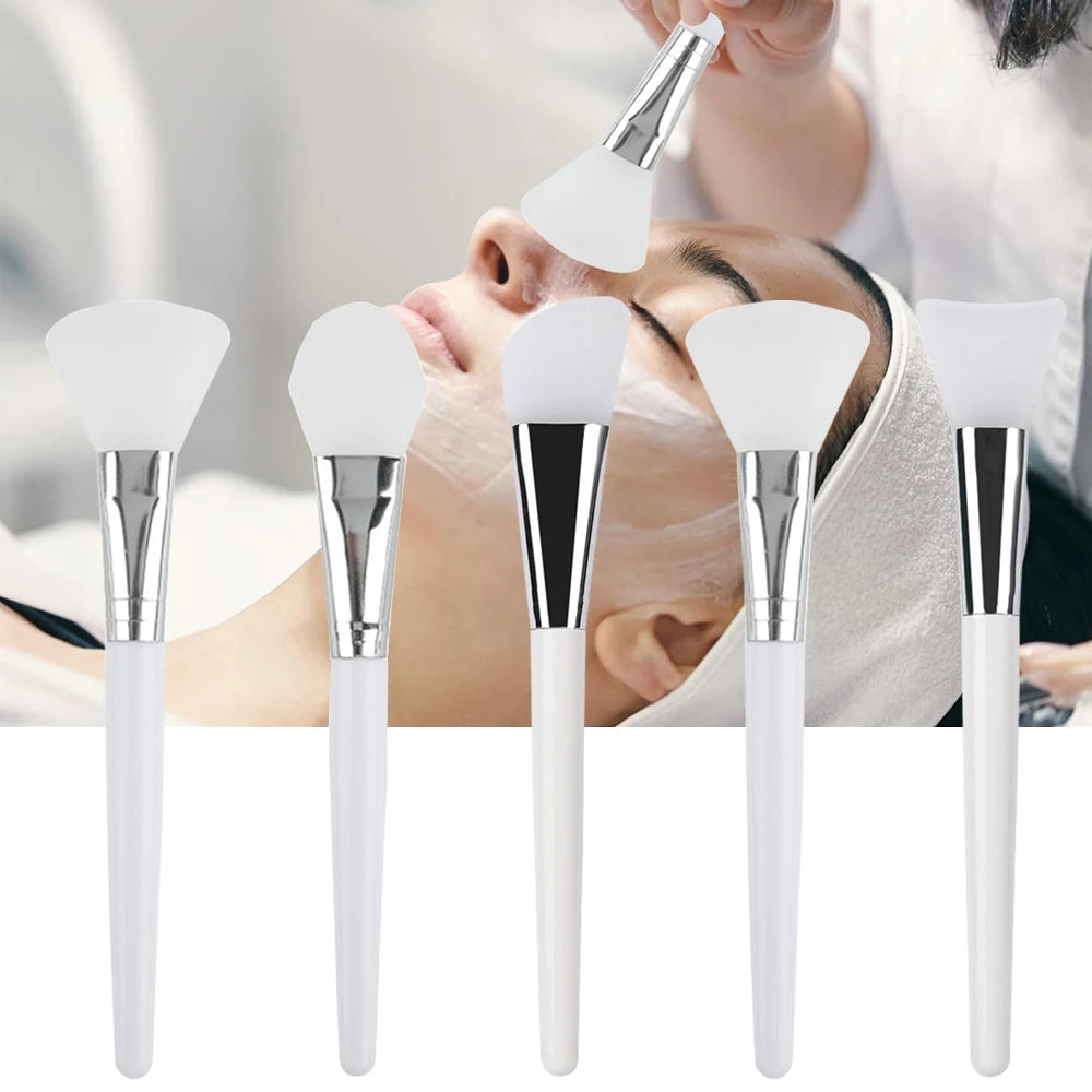 Assorted silicone face mask brushes with white handles and silver ferrules, shown applying product to a person's face.