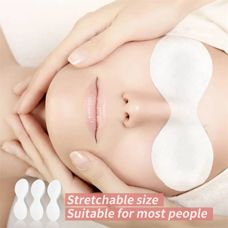 A person wearing white, disposable cotton eye pads, with three loose pads shown in the bottom left corner.