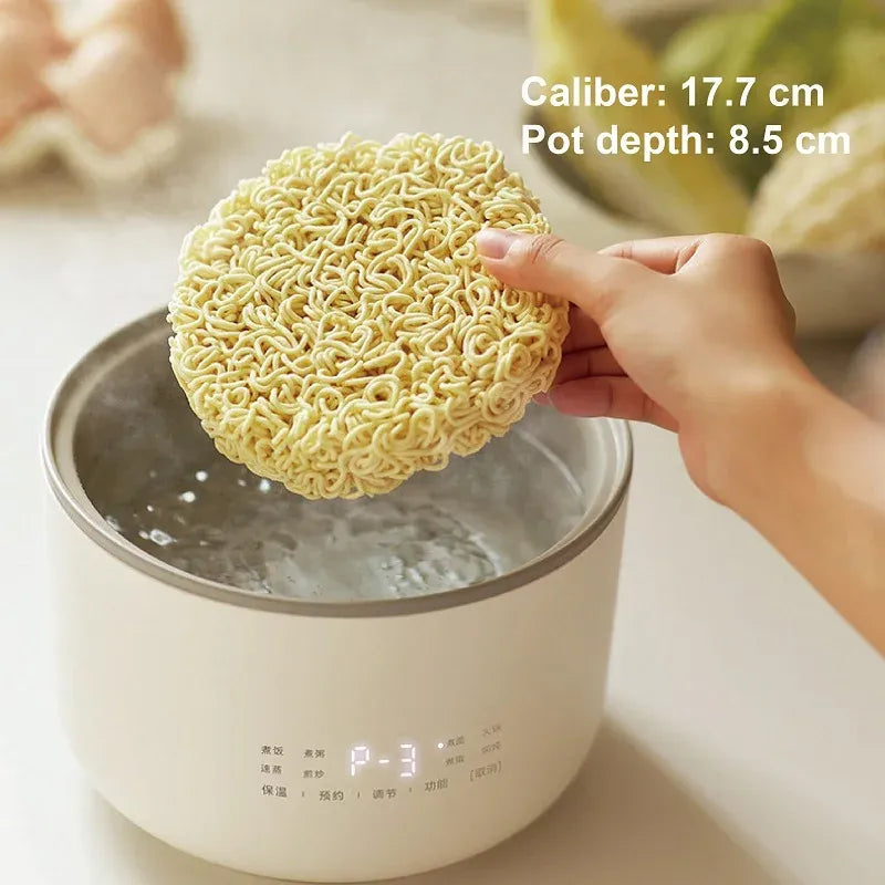 1.5L electric rice cooker steaming noodles in the inner pot, hands holding the noodles