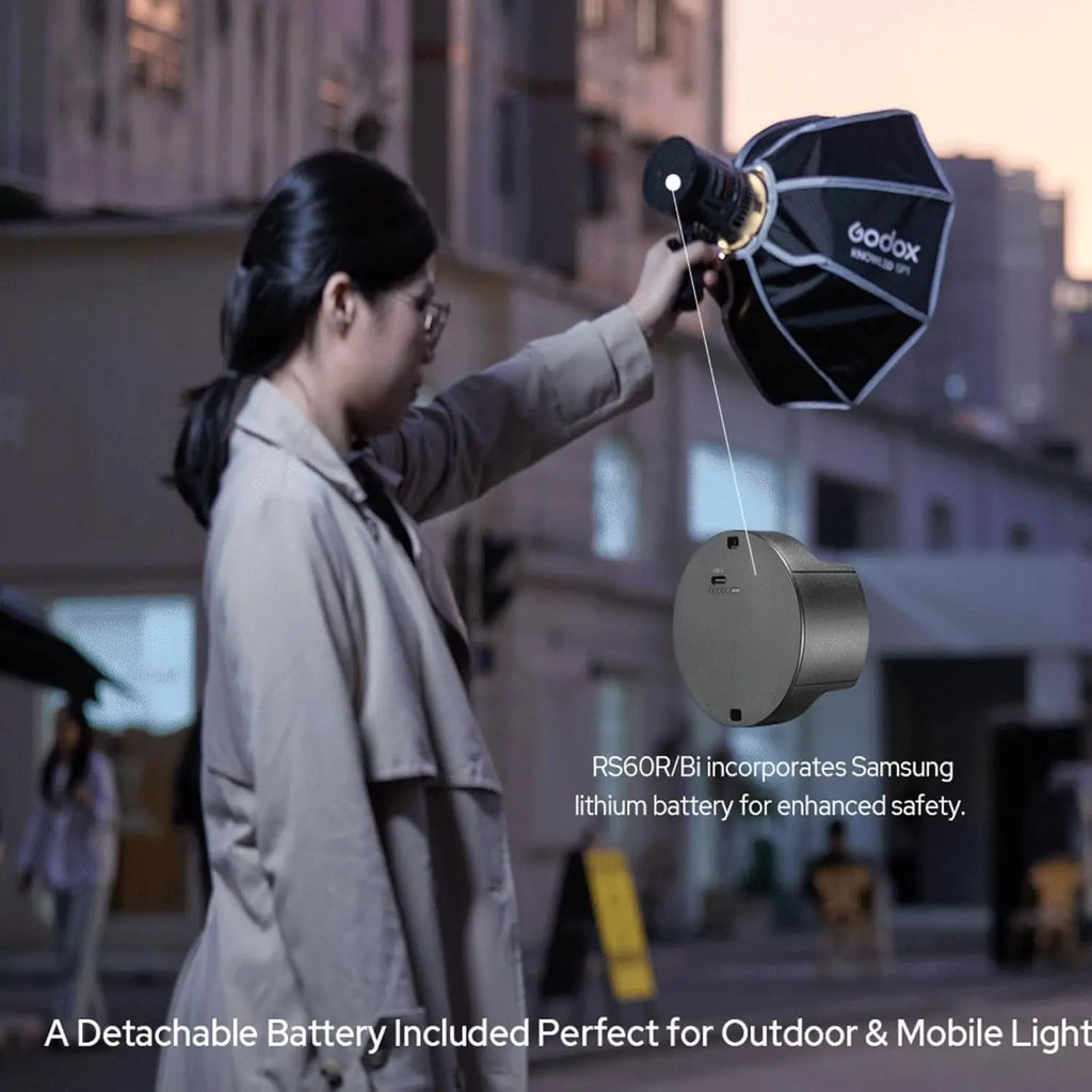 RS60R/Bi circular gray lithium battery pack for portable LED photography light, held by a person outdoors.