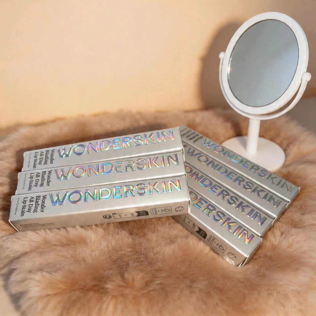 Wonderskin peel-off tattoo lip stain tubes in silver packaging with holographic logo on a soft faux fur background.