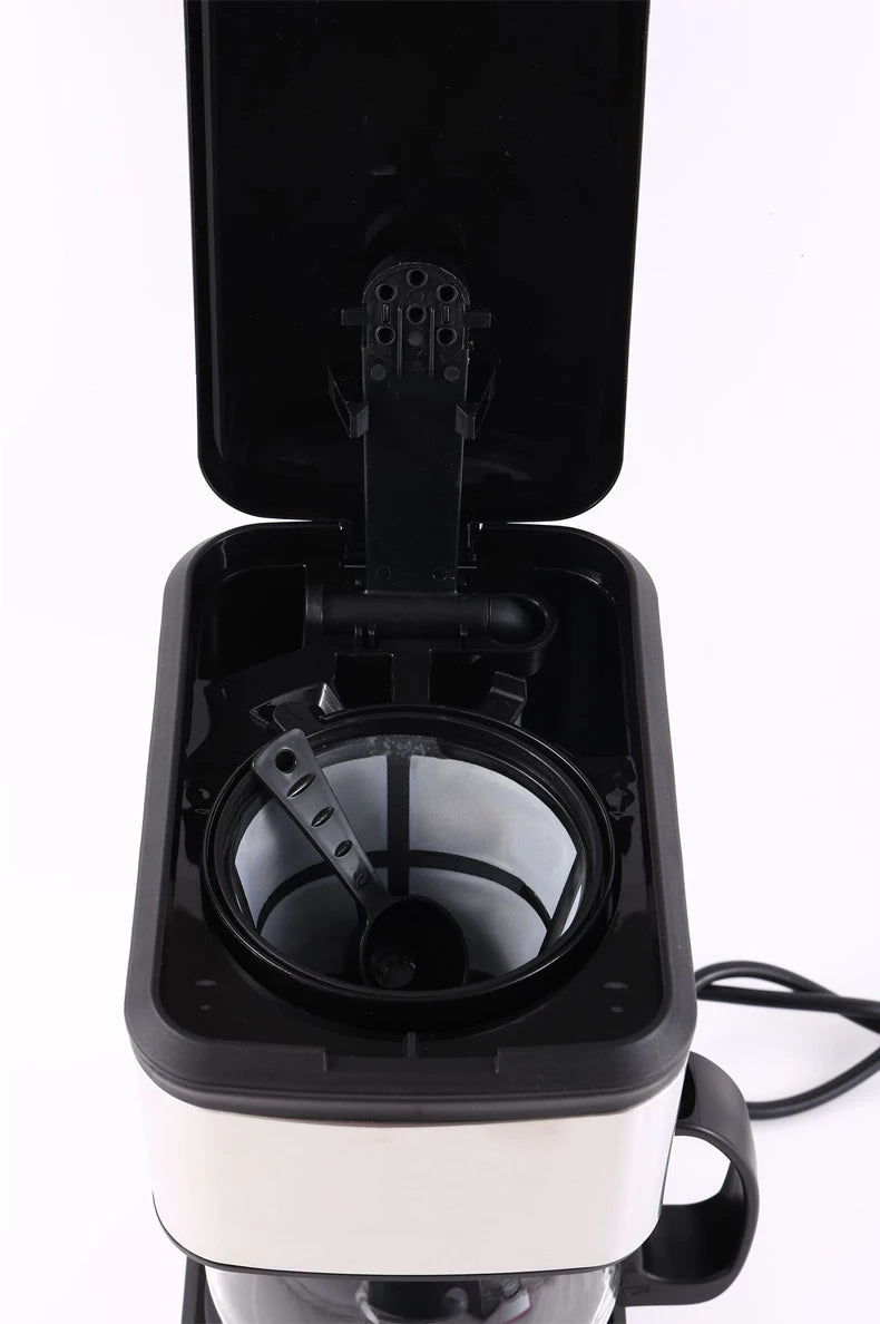 Black and white drip coffee maker with open lid, mesh basket filter, and measuring scoop inside.