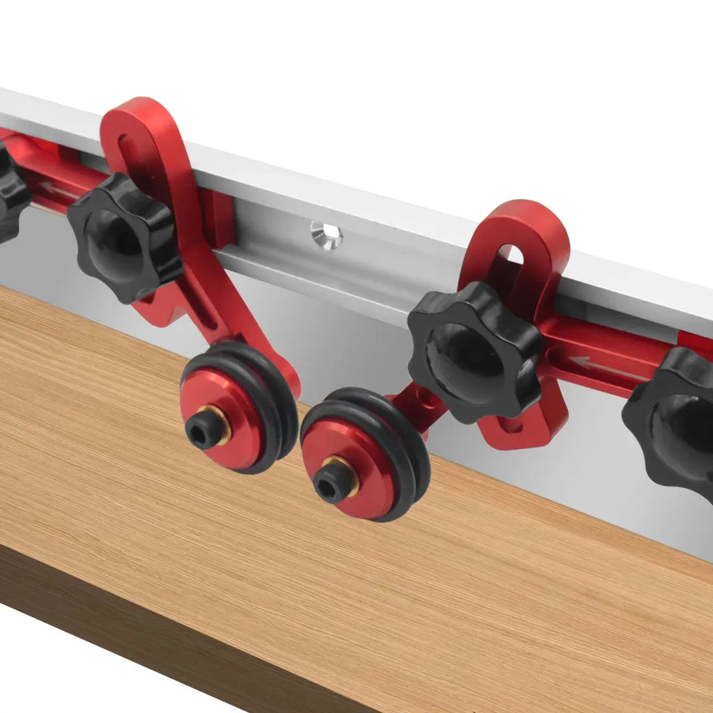 Woodworking stock guides mounted on a rail with red roller bearings and black knobs