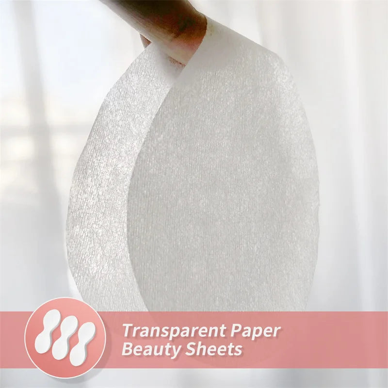 A hand holds a thin, white, translucent, oval-shaped disposable cotton eye mask sheet for DIY skincare.